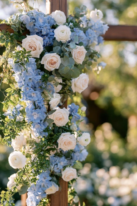 Dusty Blue Wedding Decor: Florals, Table Settings and Reception Styling 3 Dusty blue and white floral wedding arch with cascading roses, hydrangeas, eucalyptus, and romantic garden ceremony décor.