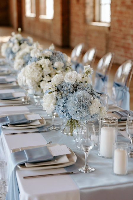 Dusty Blue Wedding Decor: Florals, Table Settings and Reception Styling 20 Minimalist dusty blue wedding tablescape with hydrangea centerpieces, white candles, blue napkins, and elegant reception décor.