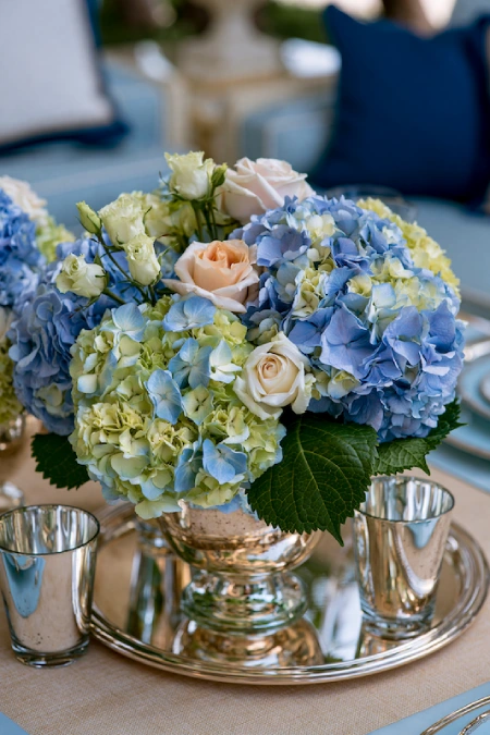 Rehearsal Dinner Centerpieces That Understood the Assignment: Easy Ideas for the Night Before the Big Night 8 Blue hydrangea centerpiece with blush roses and silver accents for an elegant rehearsal dinner table setting