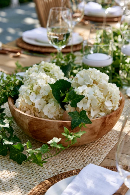 Rehearsal Dinner Centerpieces That Understood the Assignment: Easy Ideas for the Night Before the Big Night 6 Garden party rehearsal dinner centerpiece with white hydrangeas in a wooden bowl and trailing ivy accents