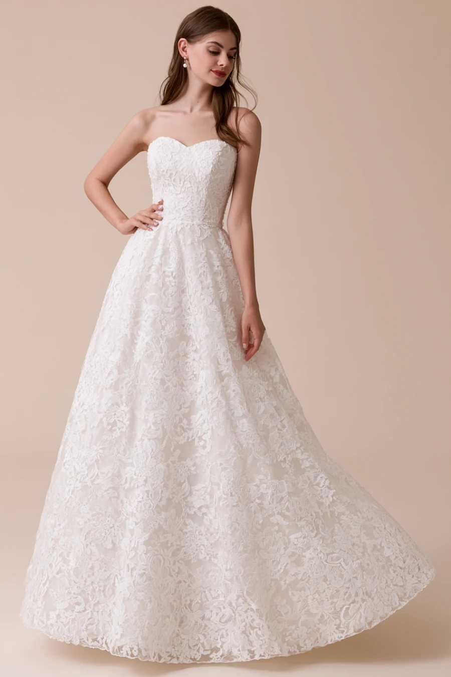 12 Timeless Lace Wedding Dress Styles We Love 8 Bride wearing a lace A-line wedding dress with a sweetheart neckline and floral lace skirt in a clean studio bridal portrait