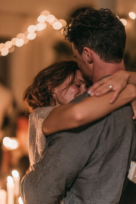 Proposal Ideas: 40 Ways to Pop the Question She'll Never Stop Talking About 4 Newly engaged couple embracing during a romantic evening dance with candlelight, string lights, and engagement ring visible