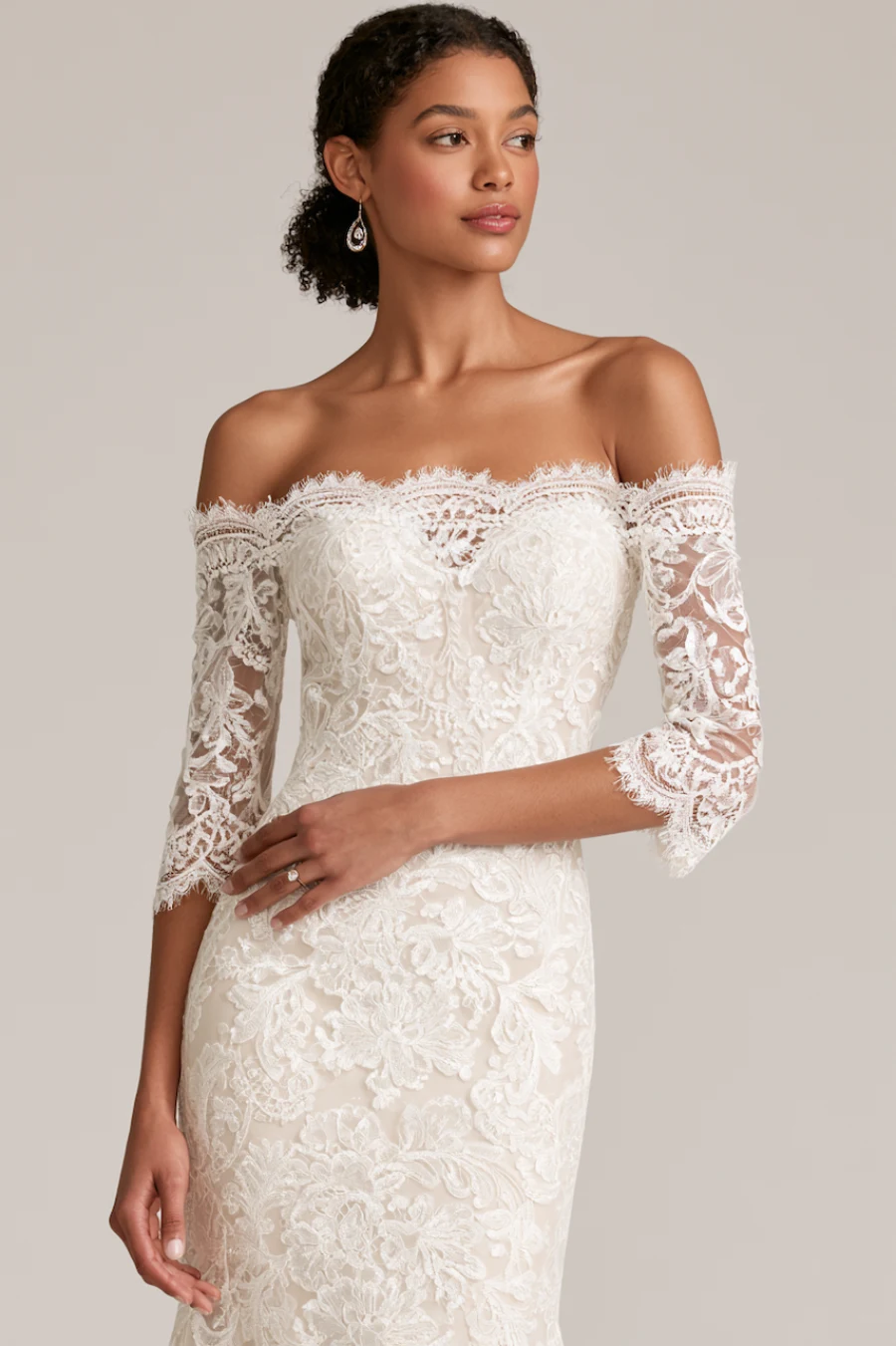 12 Timeless Lace Wedding Dress Styles We Love 12 Bride wearing an off-the-shoulder lace wedding dress with illusion sleeves, floral embroidery, and fitted bridal silhouette