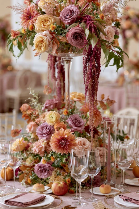 Tall floral wedding centerpiece with mauve roses, peach dahlias, cascading amaranthus, and lush blooms on a luxury reception table