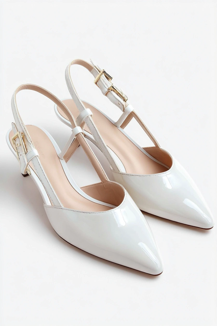 Wedding Shoes for the Bride: 27 Beautiful Ideas That Balance Style and Comfort 9 White patent leather slingback bridal flats with pointed toes, T straps, and gold buckles on a clean white studio background